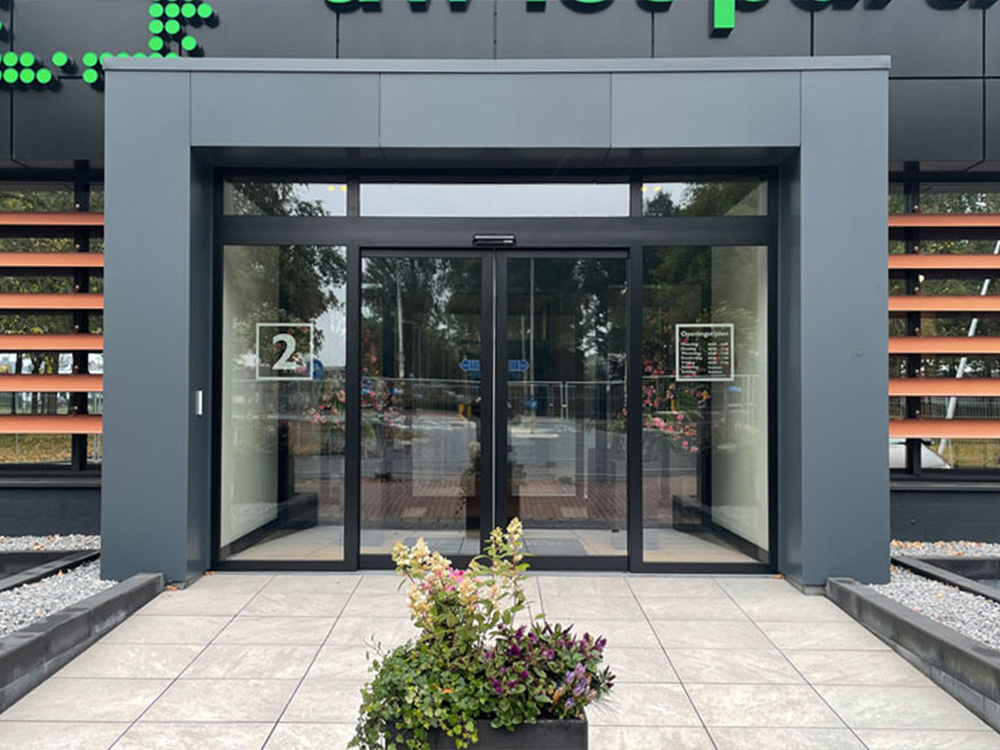 Glazen deuren van een gebouw met een plantenbak en nummer 2 zichtbaar.