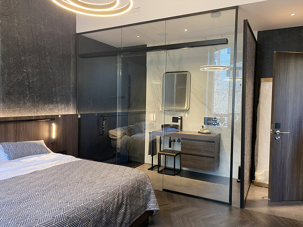 Moderne slaapkamer met glazen wand, bed, bureau en hanglamp.